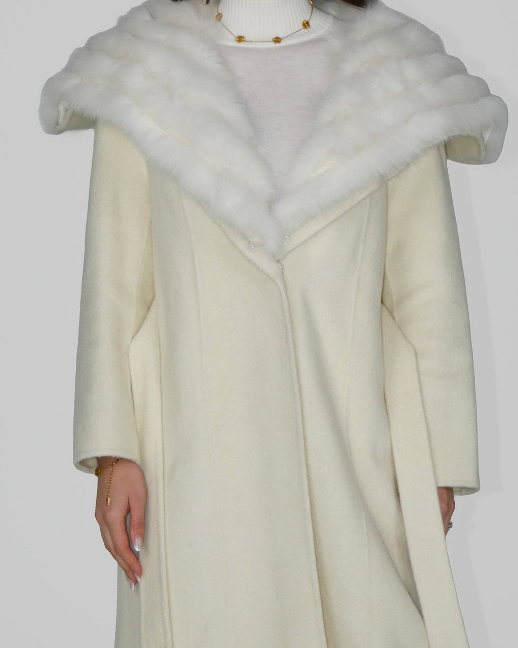 Full-length view of a long cream coat with a wide white fur collar