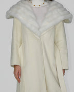 Full-length view of a long cream coat with a wide white fur collar