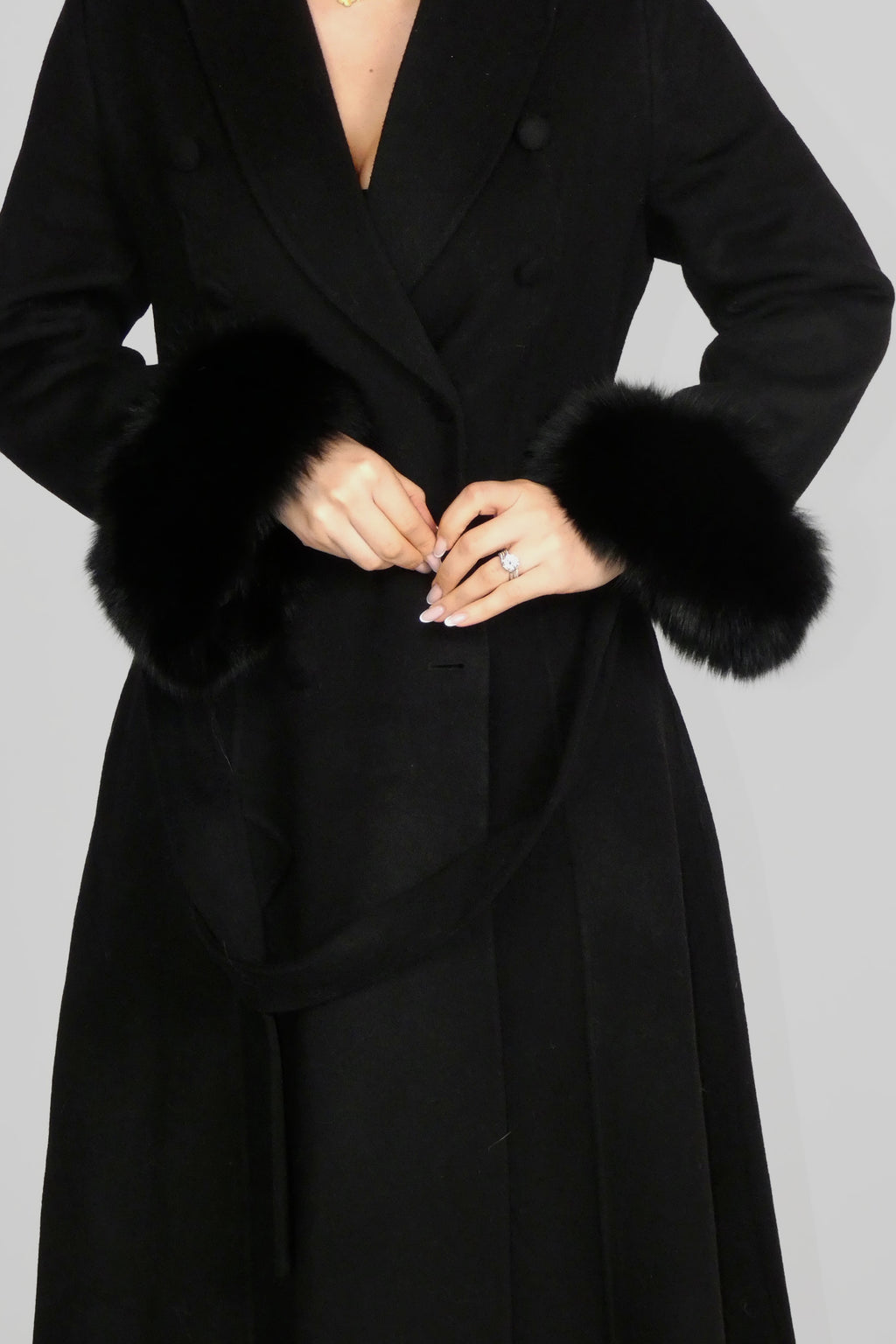 Woman wearing a long black coat, holding the front lapels