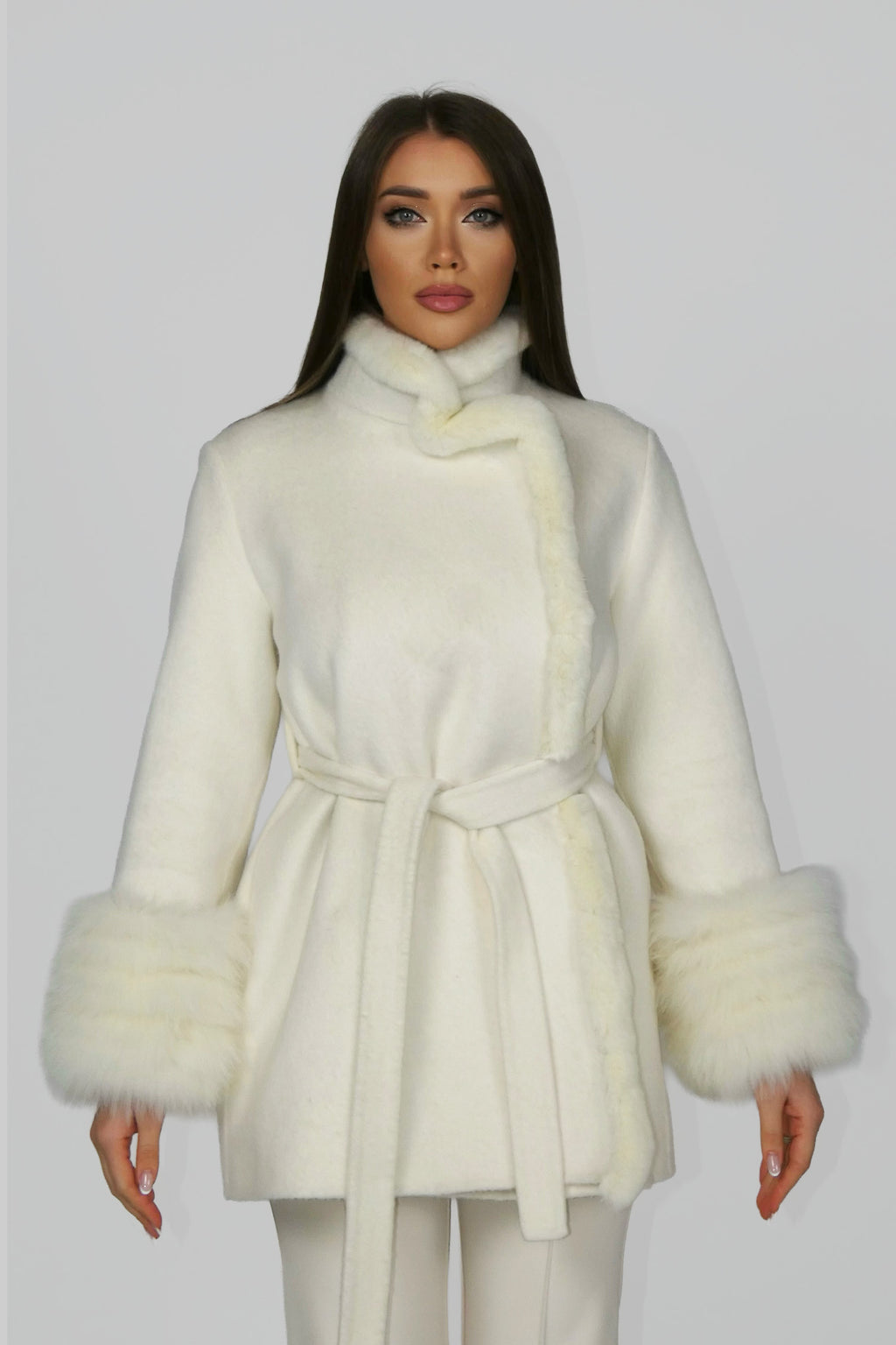 Woman wearing a white belted coat, facing forward