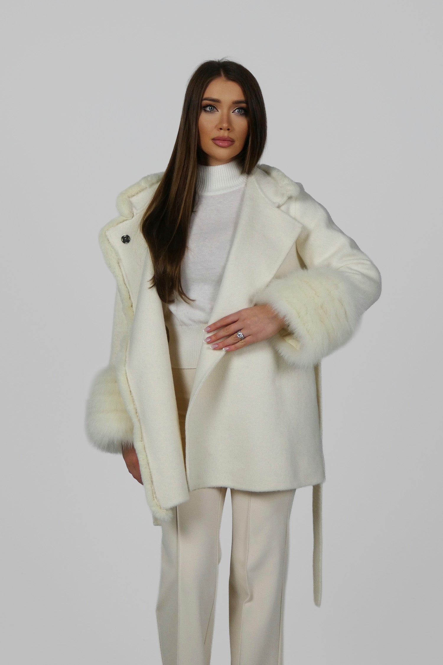 Woman wearing a white fur coat open at the front, holding the collar