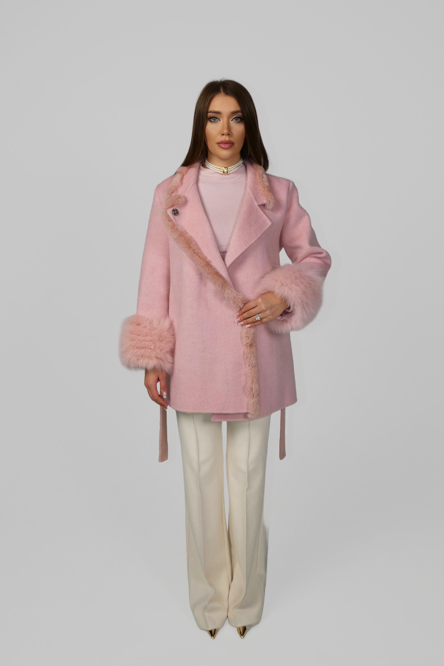 Woman wearing a pink fur coat, standing front-facing
