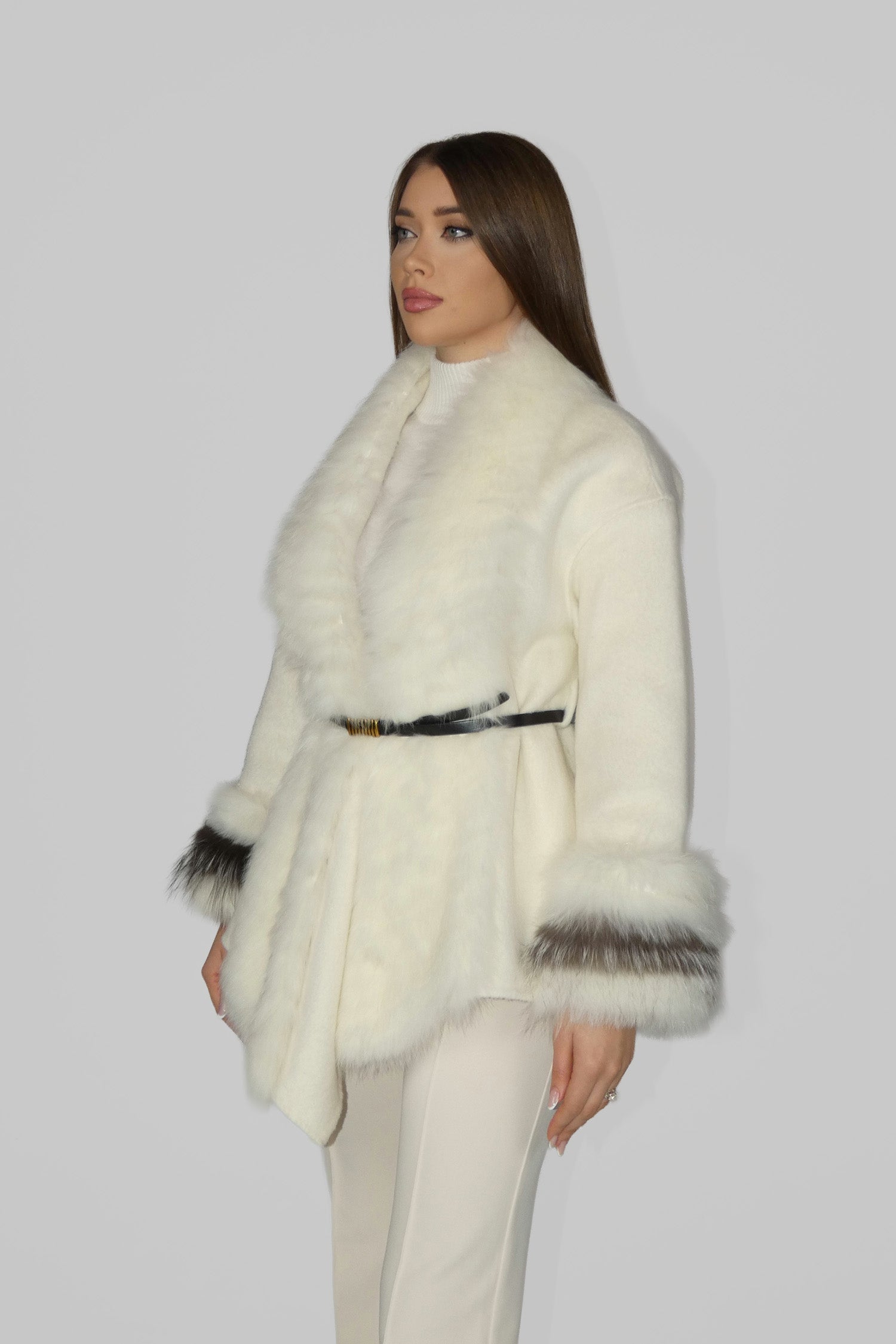 Woman wearing a white belted coat with grey fur cuffs, side angle