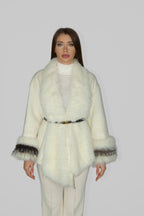 Woman wearing a white fur coat with black trim, facing forward