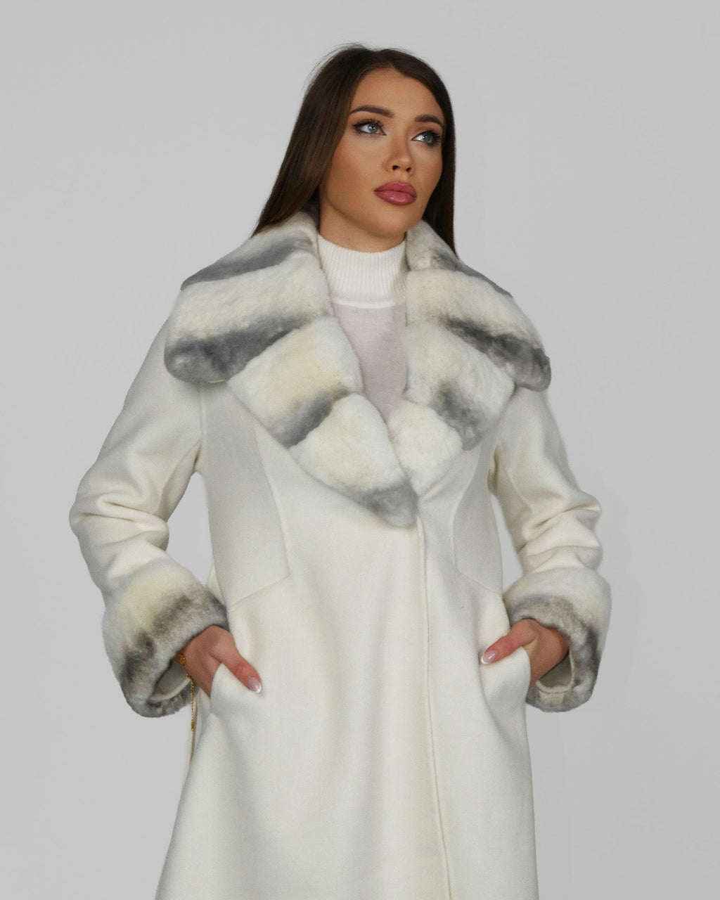 Woman wearing a white fur coat with wide sleeves, facing forward