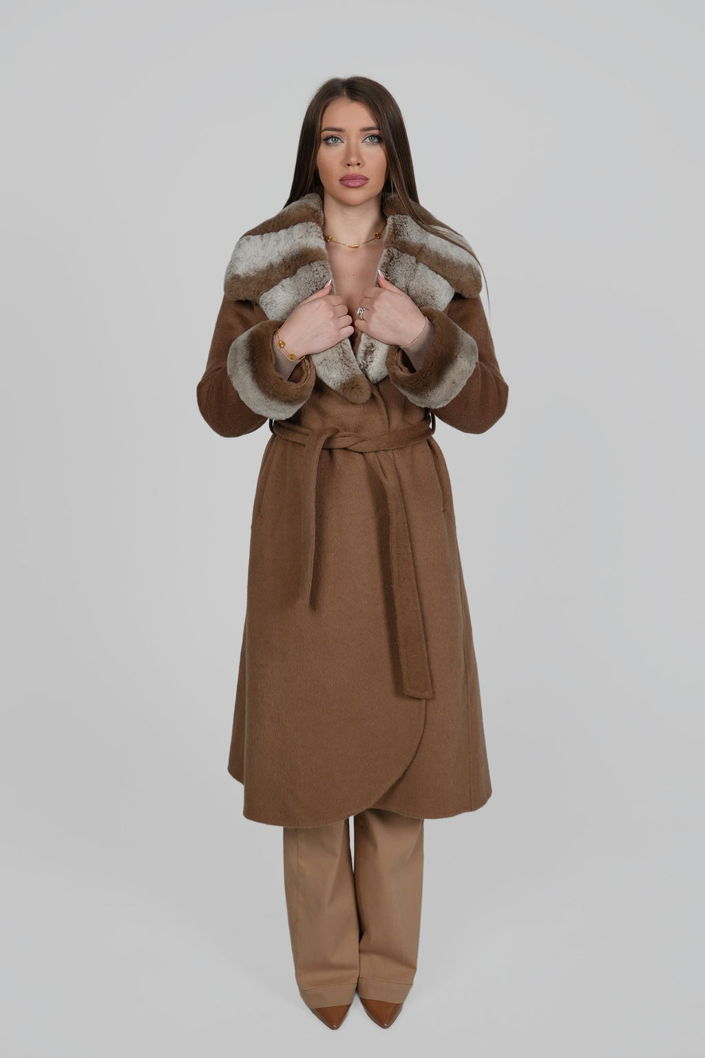 Woman wearing a brown wrap coat, standing confidently