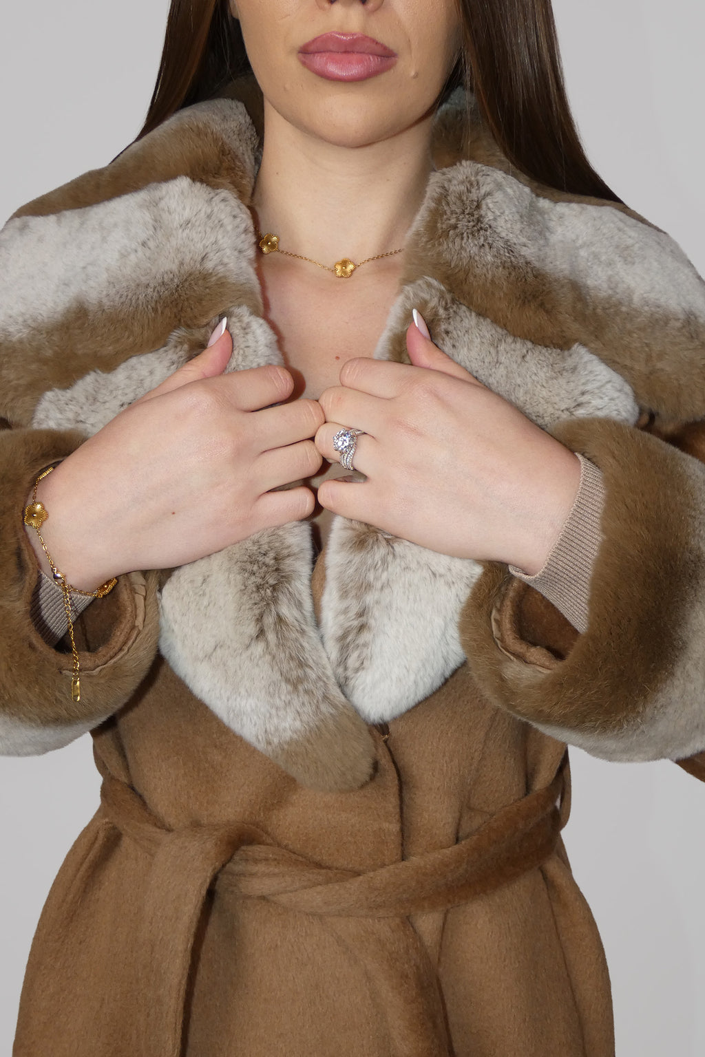 Close-up of hands adjusting the front of a brown fur-trimmed wrap coat