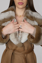 Close-up of hands adjusting the front of a brown fur-trimmed wrap coat
