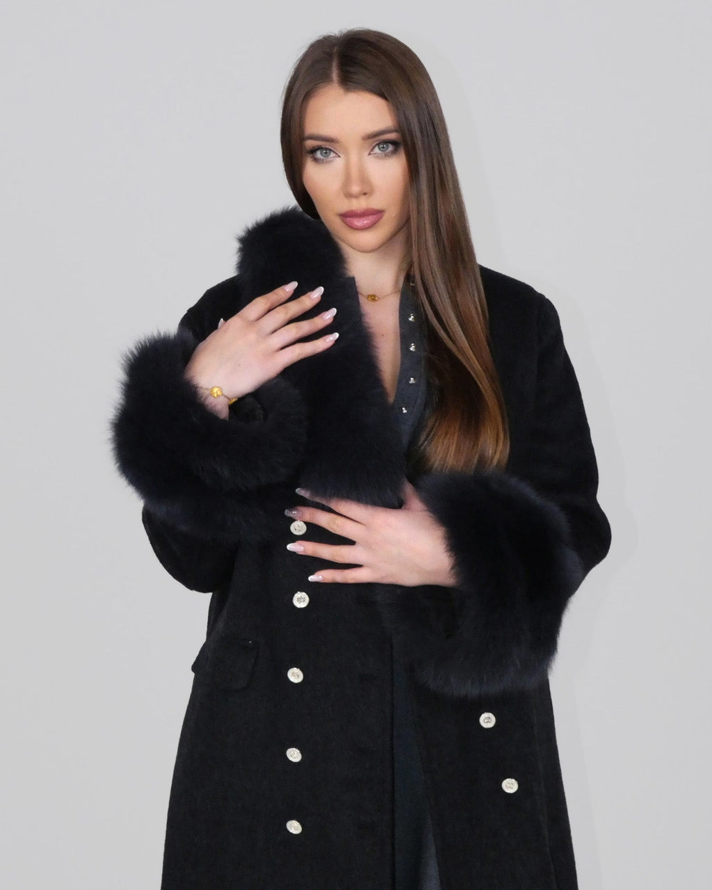 Woman wearing a black fur coat, standing facing forward with arms slightly crossed