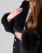 Close-up of hands holding the sleeve of a black fur coat