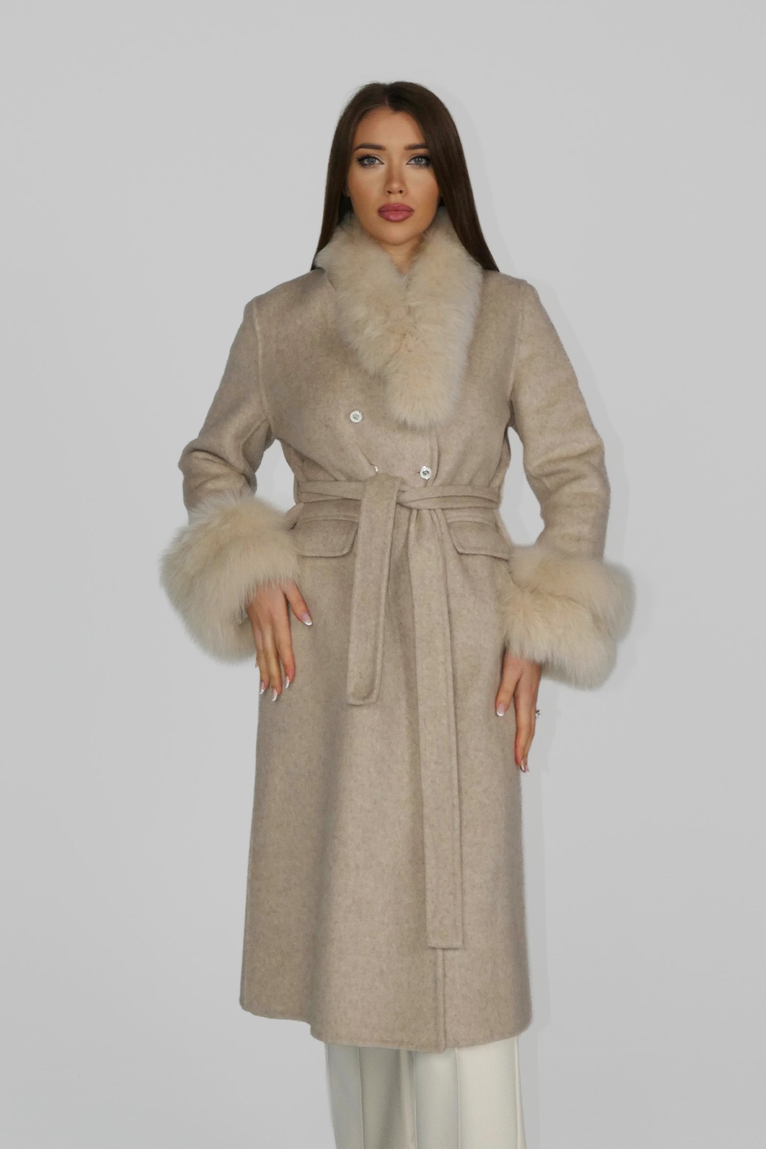 Woman wearing a beige wrap coat, standing facing forward